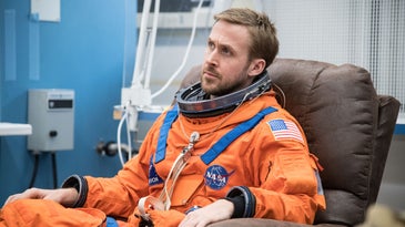 ryan gosling sitting in orange NASA uniform