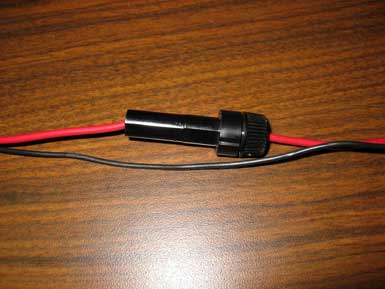 A black cylindrical wire connector on a red and a black wire.