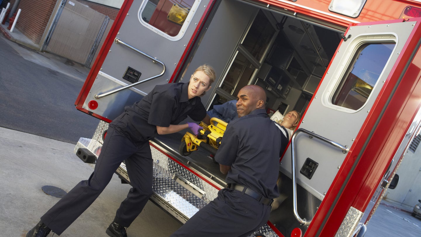two paramedics prepare to take someone out of an ambulance 