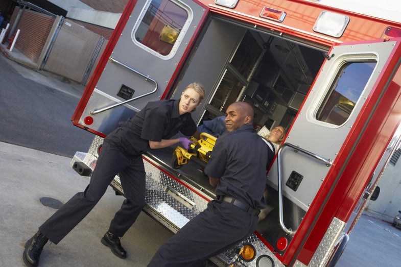 two paramedics prepare to take someone out of an ambulance