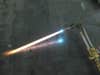 An oxy-acetylene cutting torch on a concrete floor with its flame on.