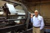 Ehsani stands next to a prototype of the machine that allows people to manufacture pipes on a truck or boat.