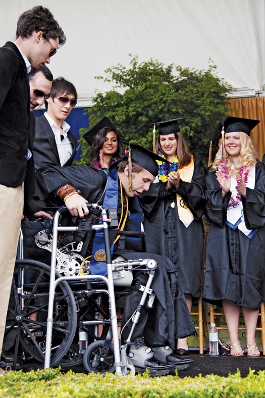 Strapped into an exoskeleton that he helped build, Austin Whitney walks across the stage at his U.C. Berkeley graduation. Below, from left: Michael McKinley, Jason Reid and Wayne Tung of the Robotics and Human Engineering Lab stand behind him.