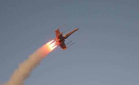 A homemade Star Wars X-wing fighter rocket in flight over the desert at Plaster Wars 2007.