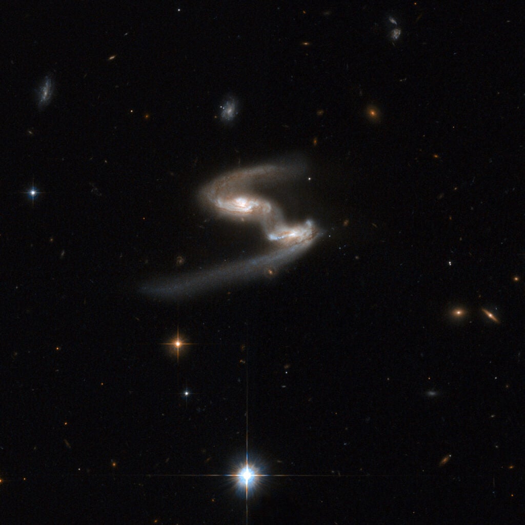 This Hubble image of ESO 77-14 is a stunning snapshot of a celestial dance performed by a pair of similar sized galaxies. Two clear signatures of the gravitational tug of war between the galaxies are the bridge of material that connects them and the disruption of their main bodies. The galaxy on the right has a long, bluish arm while its companion has a shorter, redder arm. This interacting pair is in the constellation of Indus, the Indian, some 550 million light-years away from Earth. The dust lanes between the two galaxy centers show the extent of the distortion to the originally flat disks that have been pulled into three-dimensional shapes.