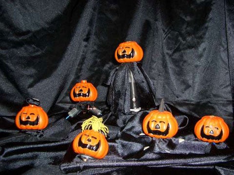 Six plastic pumpkins against a black fabric background.