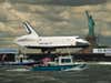 The Space Shuttle Enterprise trudges up the Hudson River in New York City on its way to the Intrepid Sea, Air and Space Museum, with some statue or something in the background. Read more <a href="http://www.nasa.gov/multimedia/imagegallery/image_feature_2276.html">here</a>.