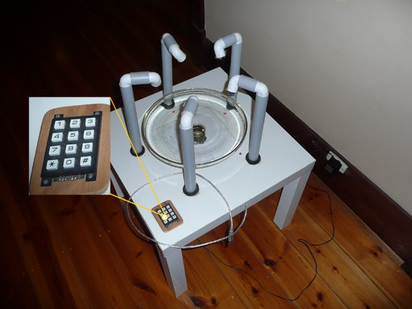 A small white table with bars coming out of it and a keypad next to it on a wooden floor.