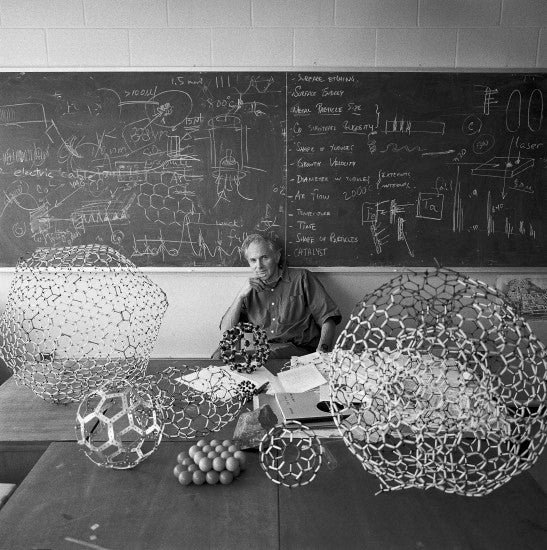 Professor Sir Harold Kroto FRS, recipient of the 1996 Nobel Prize for Chemistry, sitting in one of the seminar rooms of the University of Sussex on the day after his Nobel Prize was announced. He won the prize with Robert Curl and Richard Smalley for their discovery of C60 (Bucky balls) and other Fullerenes, models of which are shown in the foreground. [<a href="http://www.wellcomeimageawards.org">Wellcome Image Awards</a>]