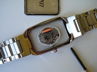 A wristwatch with the back of the timepiece removed.