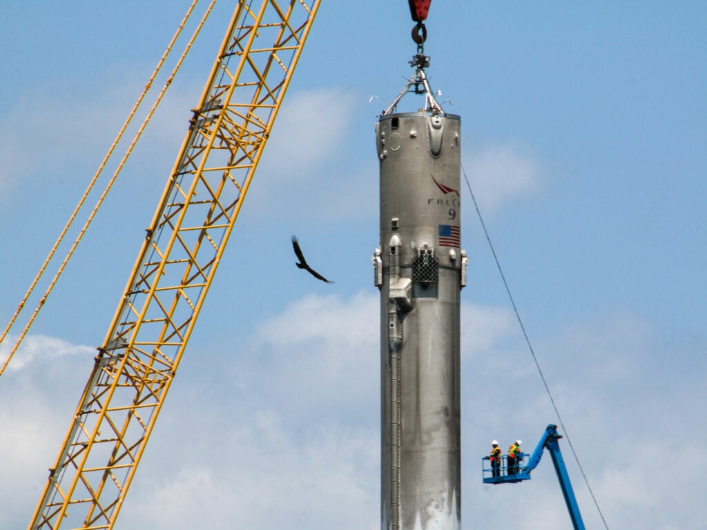 Workers tie a tether to the landed rocket booster.