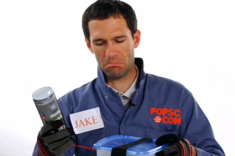 A person wearing blue Popular Science coveralls holding a can of compressed air.