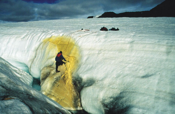 The Sulfur Springs of Borup Fiord Pass, Ellesmere Island - about 1,000 miles north of the Haughton Crater -- provide an ideal habitat to prepare for a geological study of Jupiter's moons. <a href="http://planetary.org/explore/topics/planetary_analogs/borup_fiord.html">The Planetary Society</a> has funded a research project there to learn more about the biology, geology and chemistry of the spring. It's unique on Earth: waters flow or seep onto the surfaces of glaciers, and elemental sulfur, gypsum, and calcite precipitate from their waters. At the same time, hydrogen sulfide gas is released to the air. The deposits stain the surface of the ice and leave telltale landforms behind. The unusual chemistry, in combination with the extremely cold and dry environment, make these springs an analog for hydrothermal sites beneath ice on Mars and Europa. Pictured: Researcher Stephen Grasby samples sulfur spring discharge at Borup Fiord Pass.