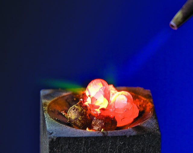 A person melting diamonds in a ring with a torch.