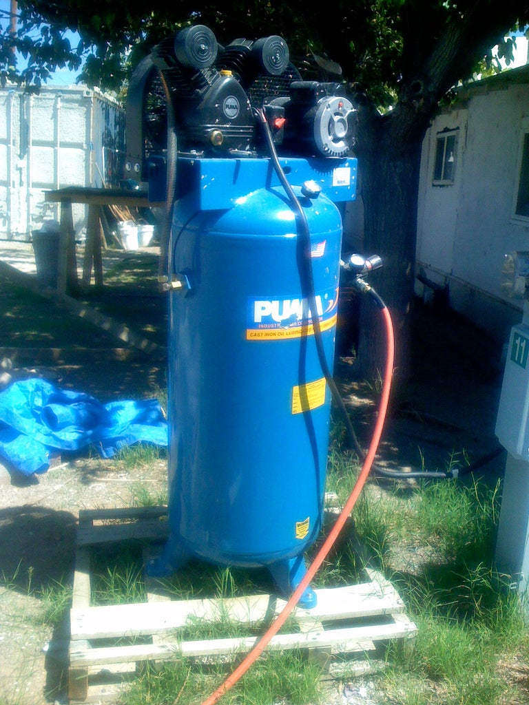 A blue 60-gallon air compressor on a lawn.