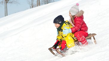 two children sledding downhill