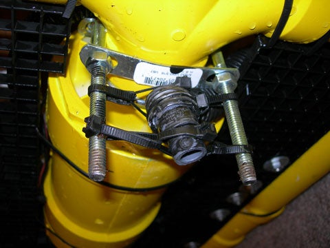 A black thruster nozzle at the end of a hose running from a bilge pump on a yellow homemade ROV.
