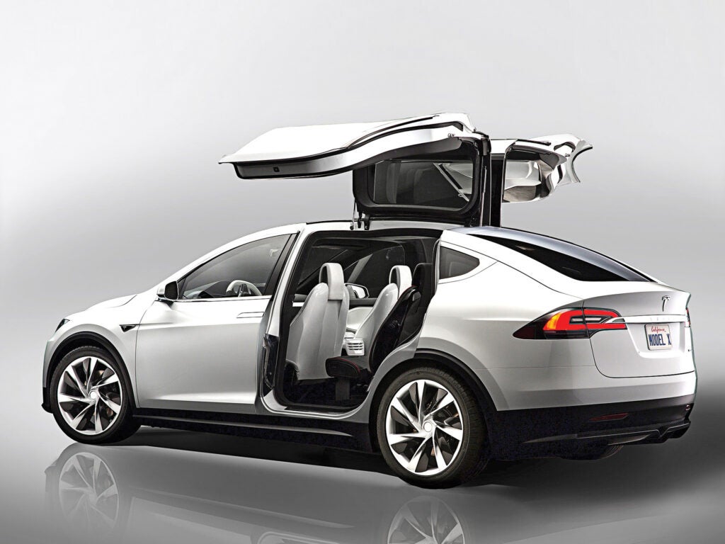 A side view of the Model X vehicle, gull-wing rear doors open