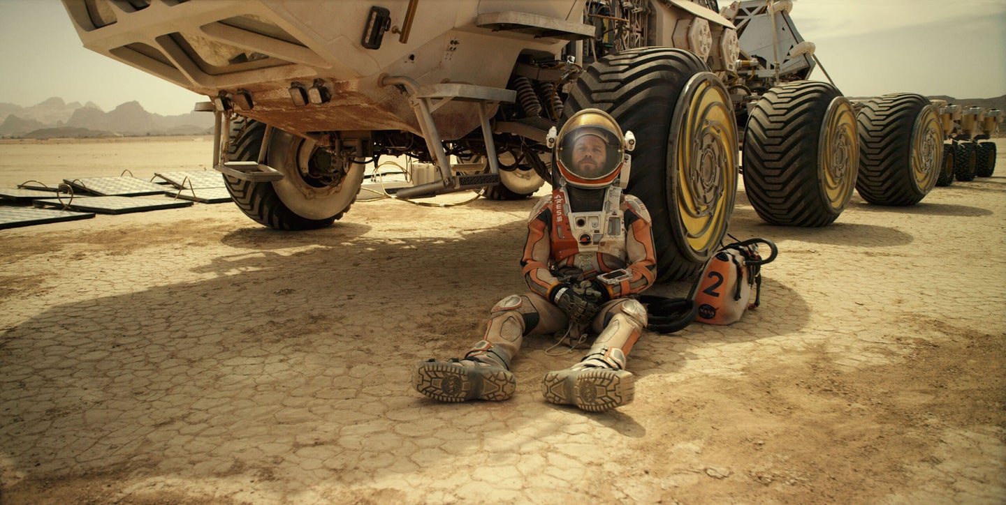 Matt Damon leans against a rover
