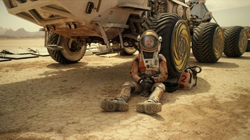 Matt Damon leans against a rover