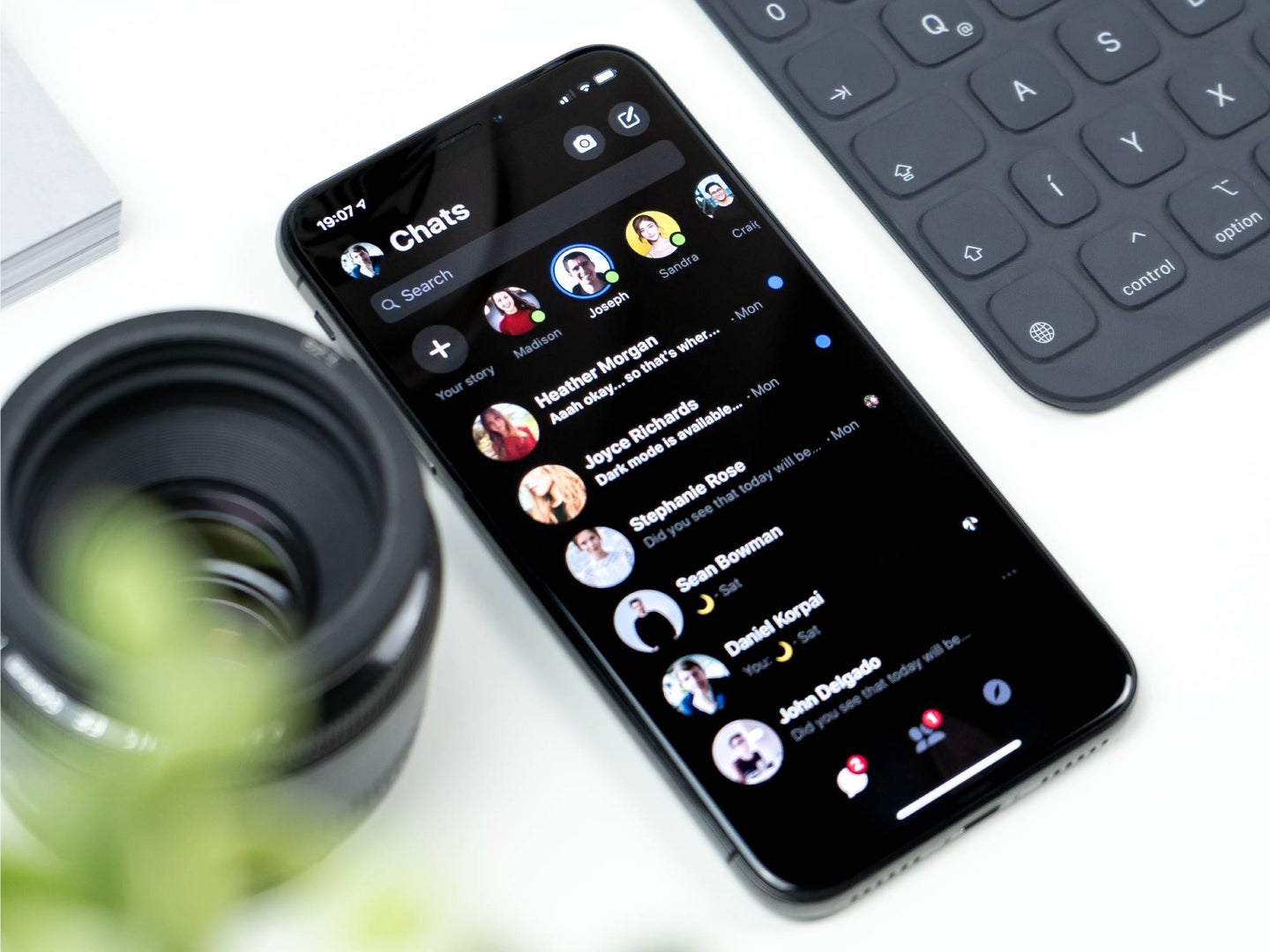 An iPhone on a white table showing Facebook Messenger in dark mode.