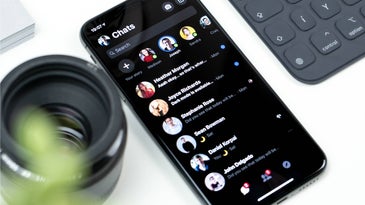 iphone on white table showing facebook messenger on dark mode