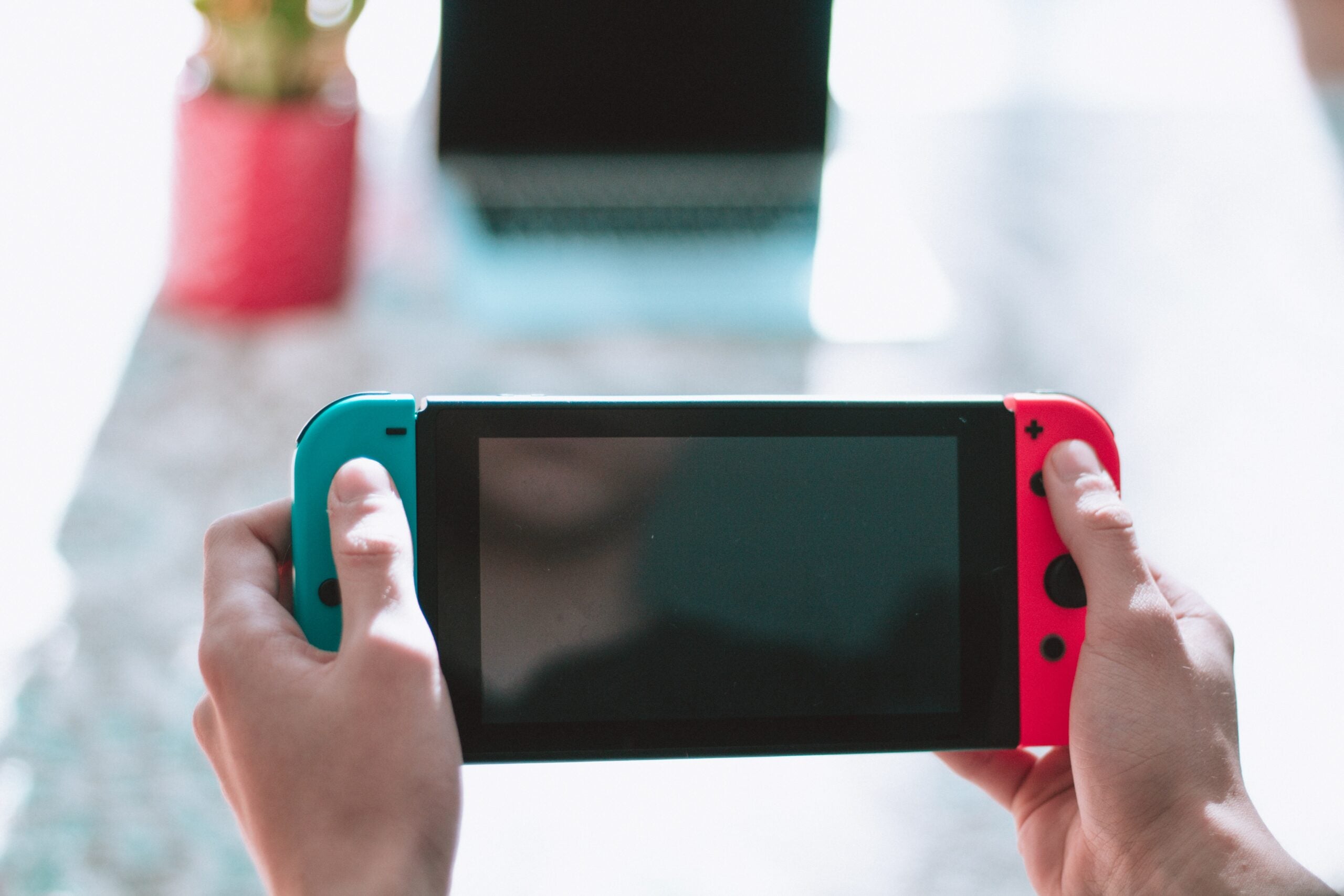 A person playing with a Nintendo Switch over a white marble countertop during the day.