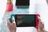 A person playing with a Nintendo Switch over a white marble countertop during the day.