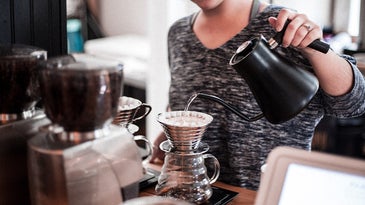Woman pouring water from an electric kettle into a pour over coffee maker