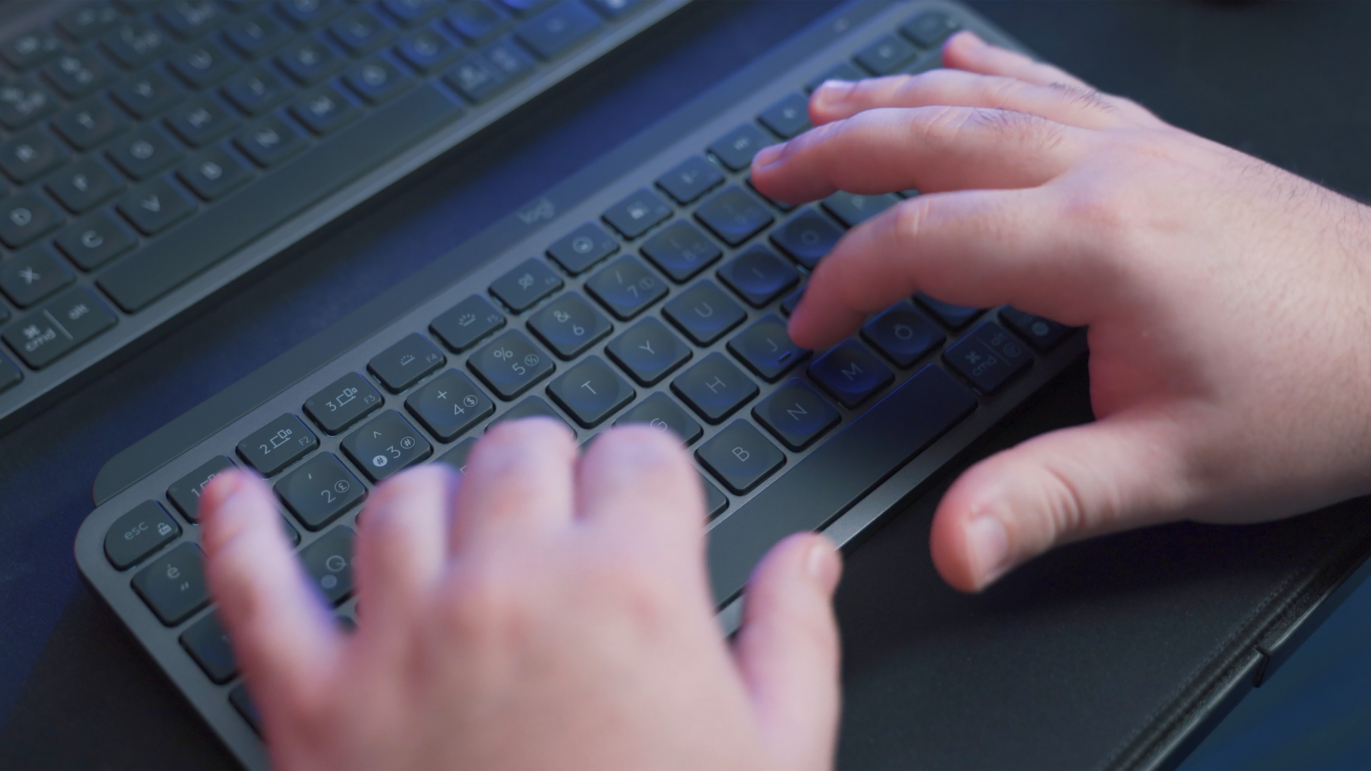 A person's hands on a smaller black keyboard in front of a larger black keyboard, perhaps figuring out how to use mouse keys to navigate their computer without a mouse.