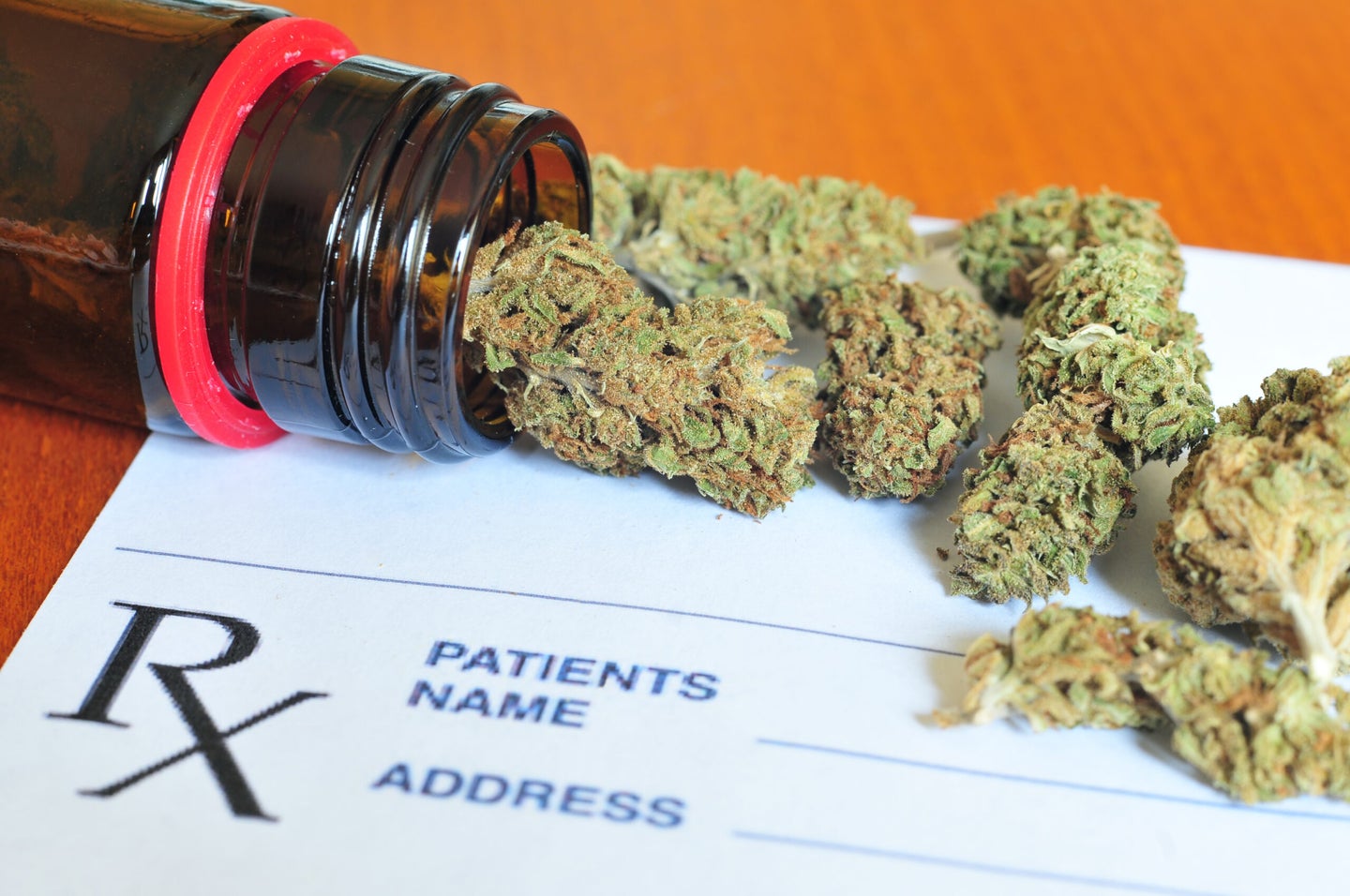 Bits of marijuana lay on a table on top of a doctor's prescription pad.
