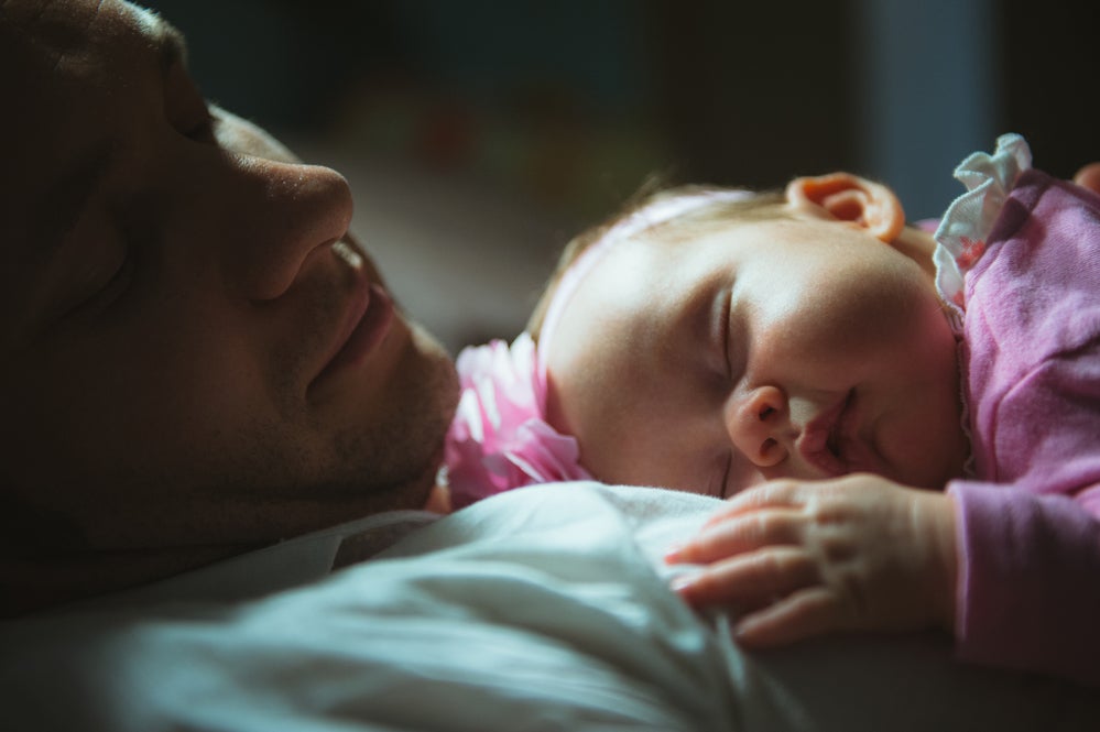 Image of young dad with cute little daughter in his arms. Father and newborn baby child indoor.