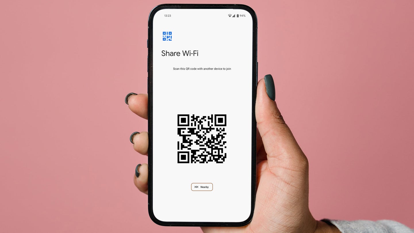 A hand holding a phone showing a QR code for sharing WiFi.