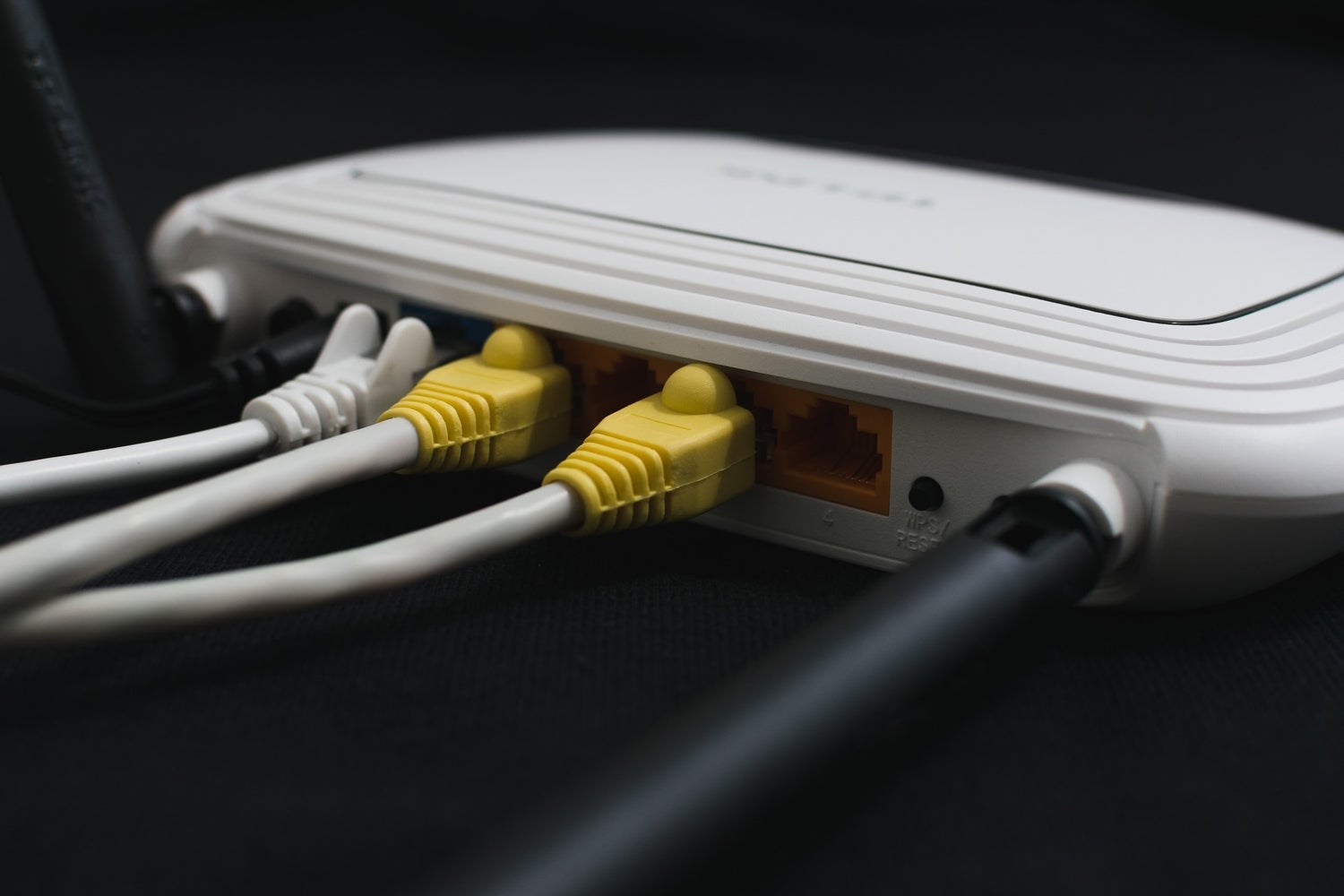 A white WiFi router with wires plugged into the back.