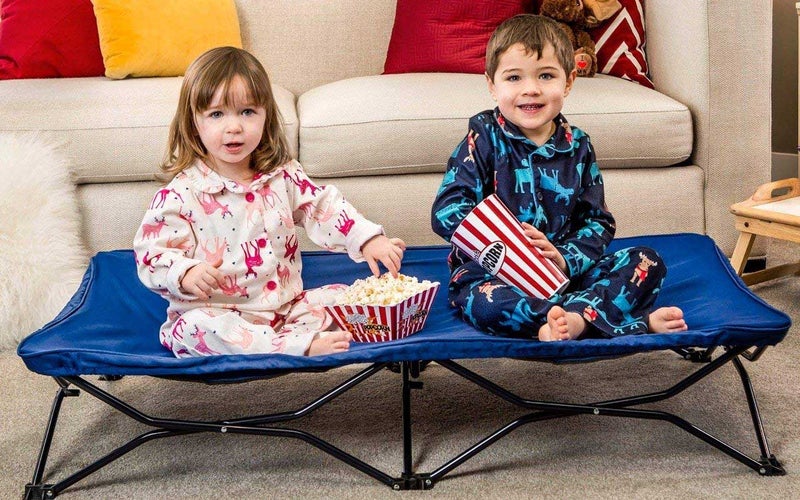 two children sitting on a portable cot