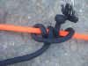 a rolling hitch knot with orange and black paracord