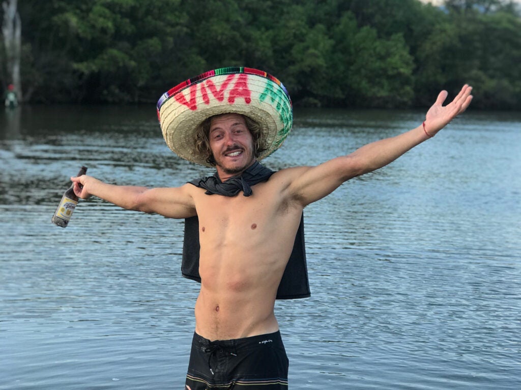 Shirtless man in the water with sombrero and a beer