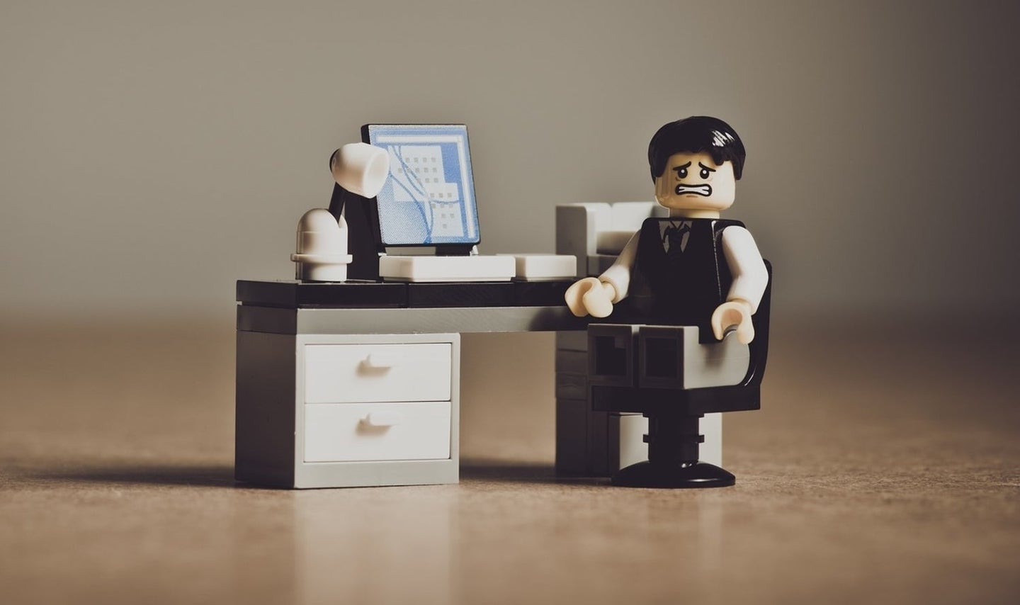 A Lego figure sitting at a desk looking desperate because he just got hacked.
