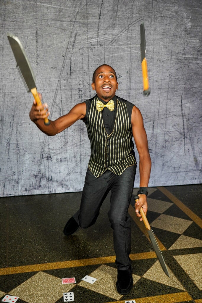 performer juggling knives in vest and bowtie