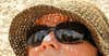 person wearing sunglasses hat and sunscreen on nose
