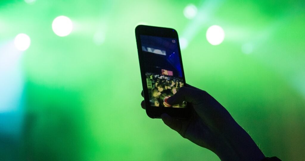hands holds a phone in concert to take a picture