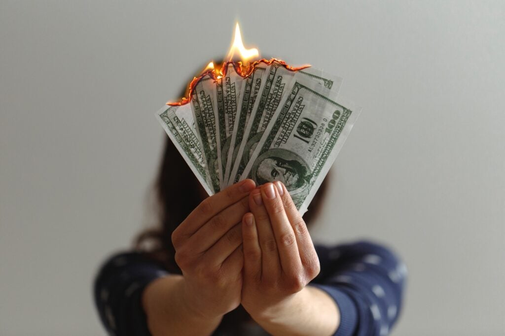 person holds burning 100 dollar bills