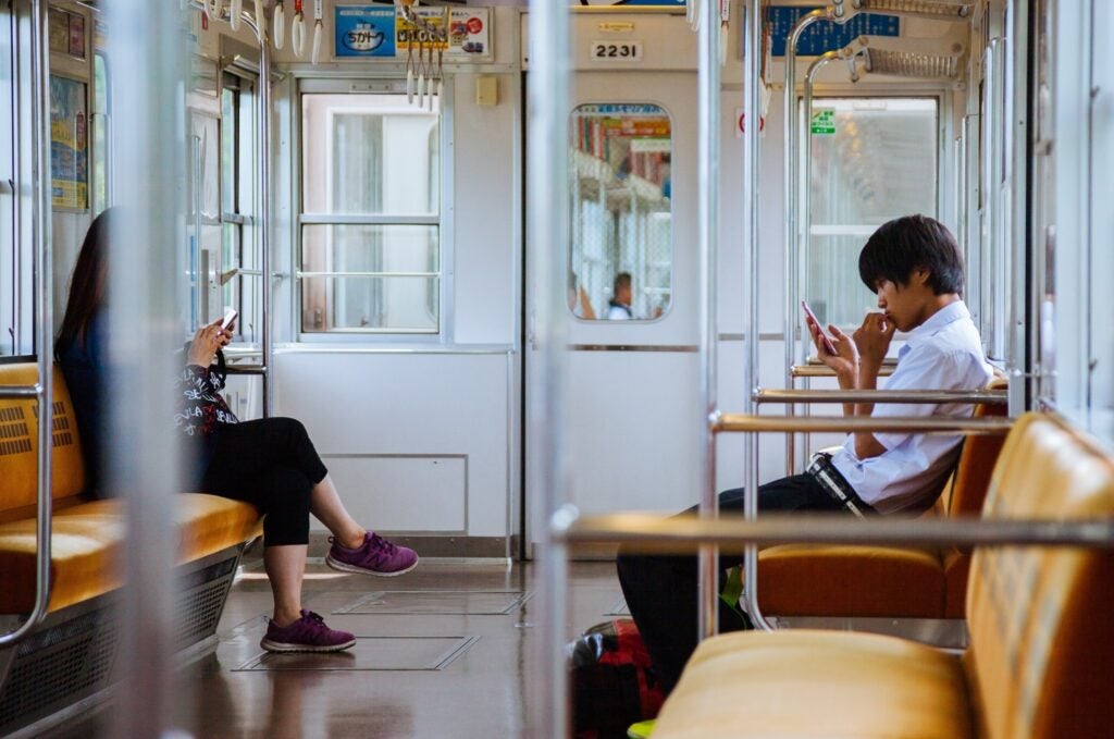 two people reading on their phones while sitting in the train