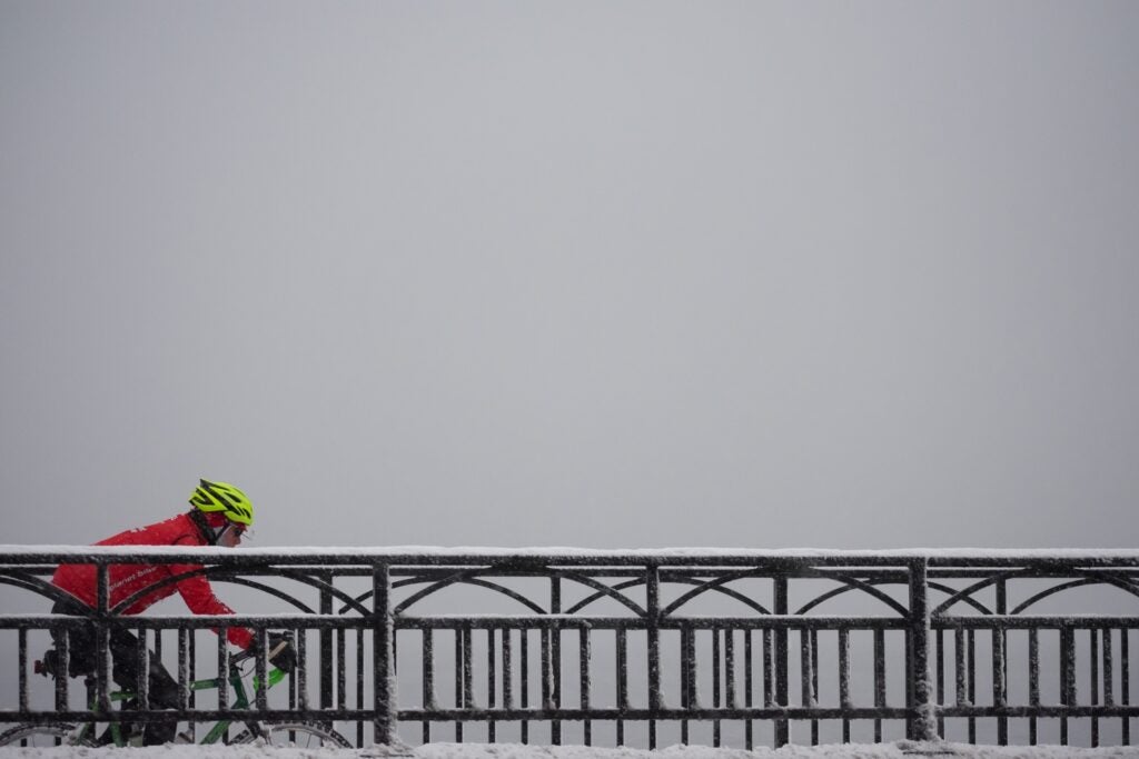 person riding a bike in the snow, wearing bright colors and a bright helmet