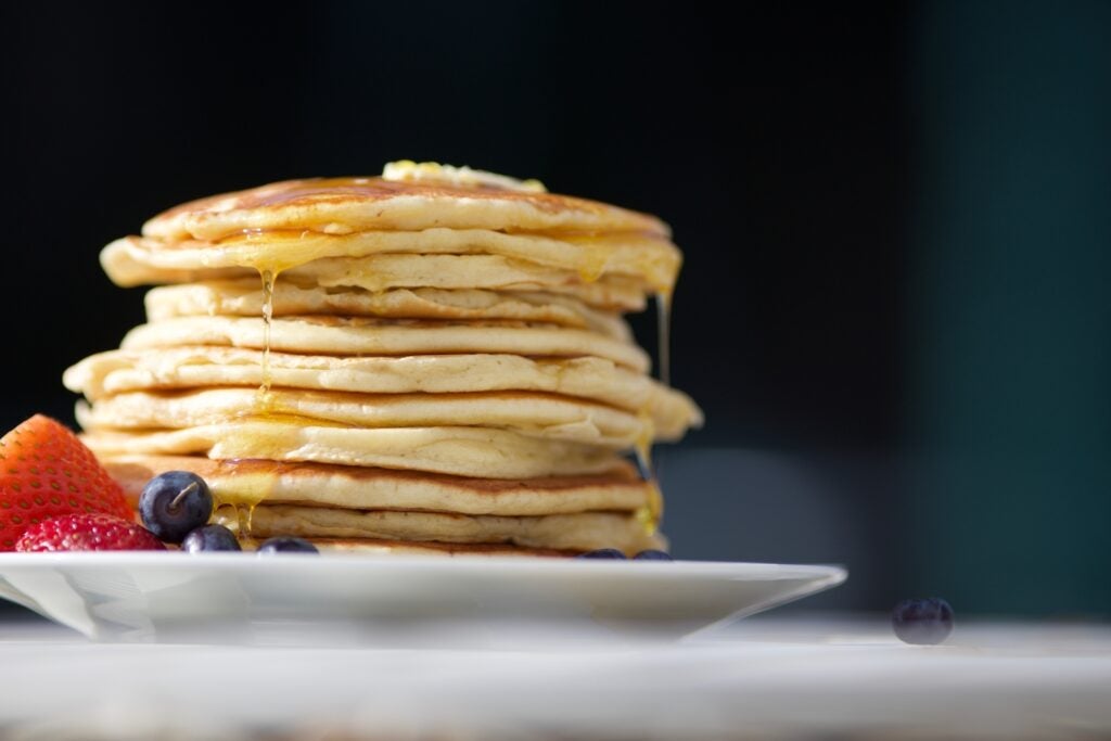 stack of delicious pancakes with blueberries and strawberries on the side