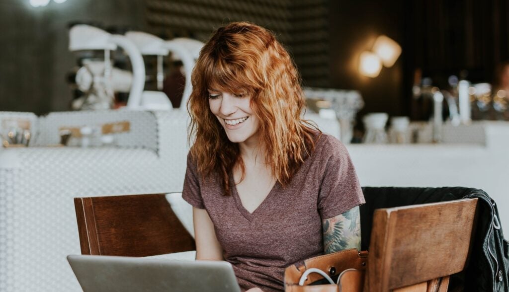 woman in coffee house on laptop smiling