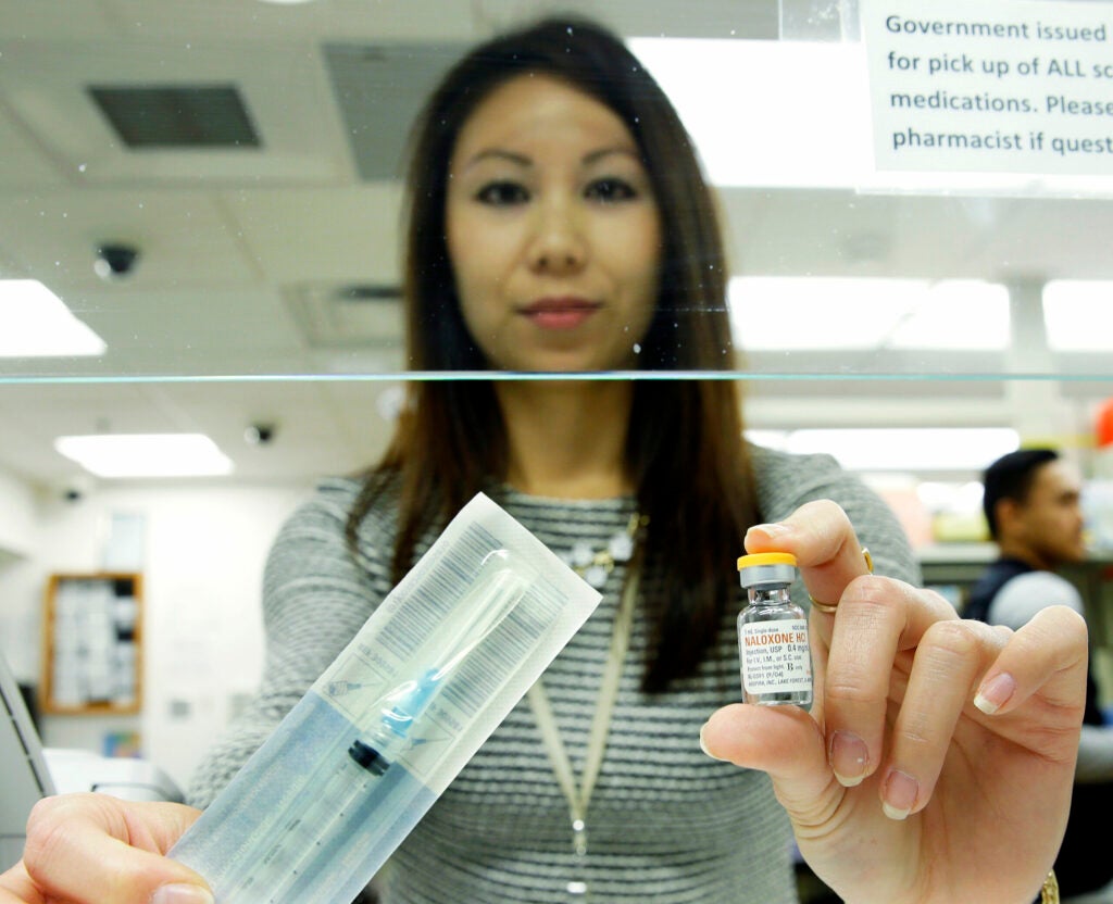 A pain pharmacist holding a vial of naloxone