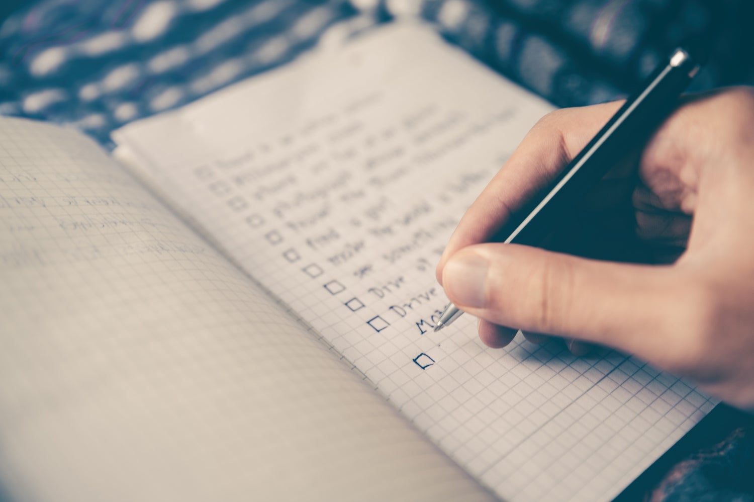 A person writing a to-do list in a notebook.