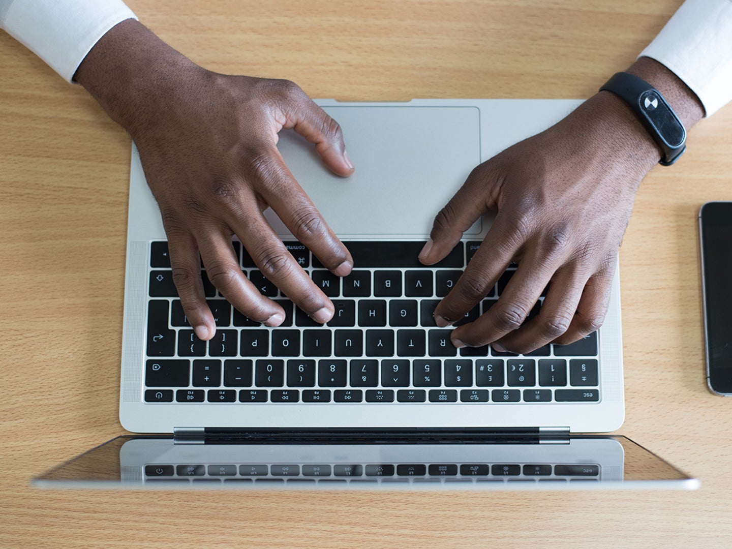 A person's hands on a Macbook keyboard.