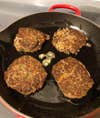 veggie burgers cooking in a cast iron pan